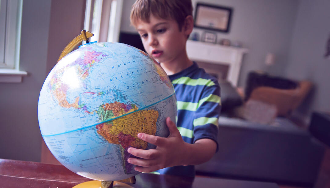 little boy looking at globe
