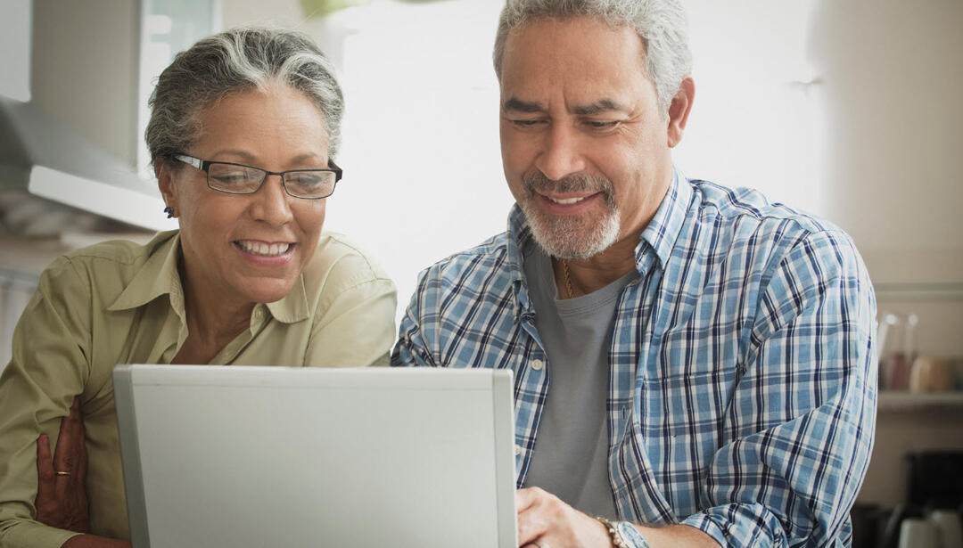 Hispanic couple using laptop in kitchen