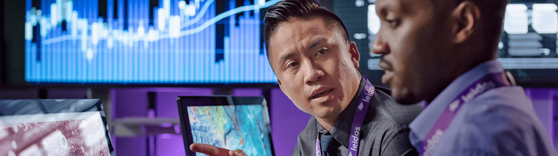 Two coworkers collaborating in front of computer monitors