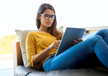 Woman sitting on couch on tablet